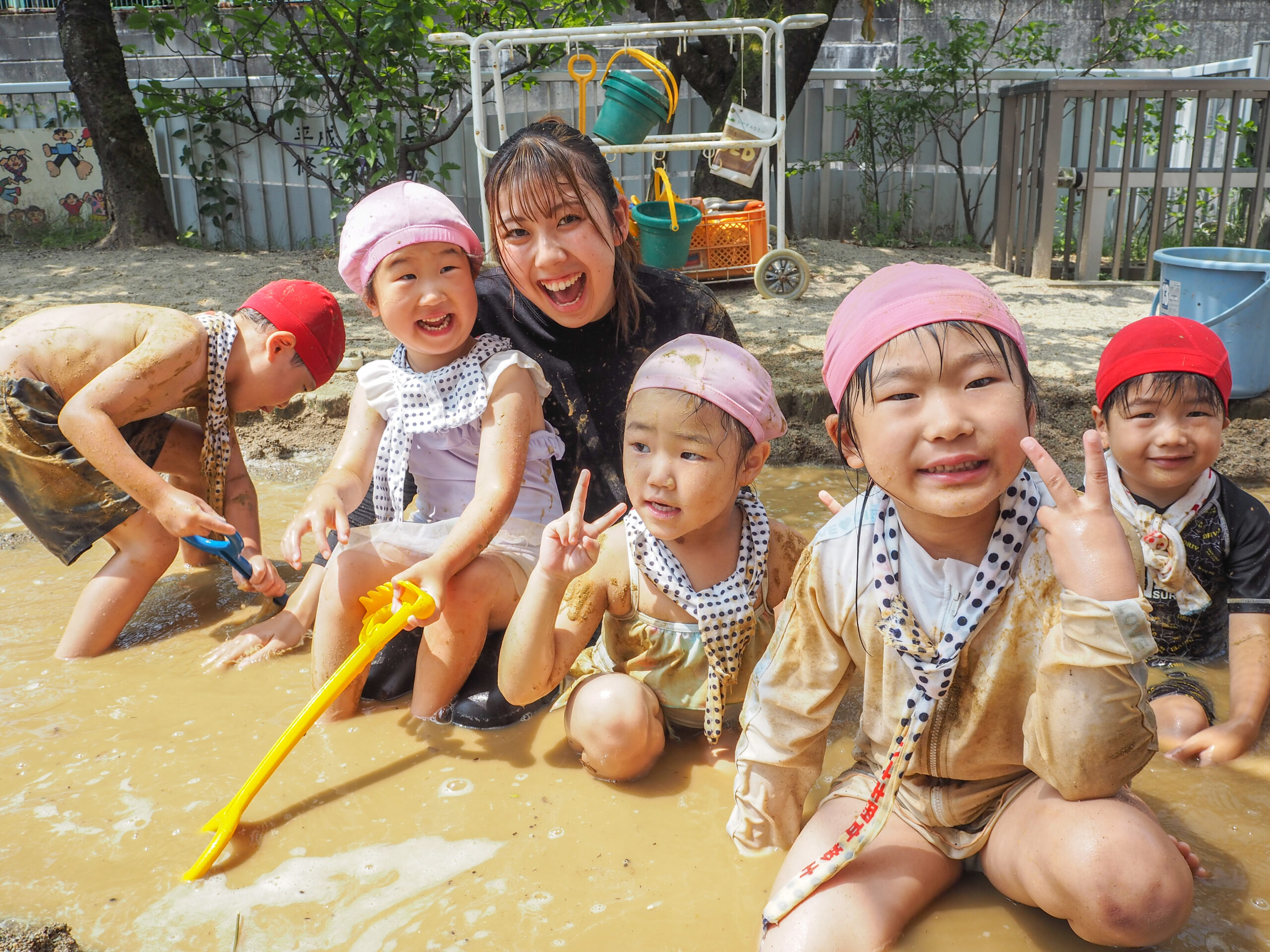 泥んこ遊びをする園児と先生