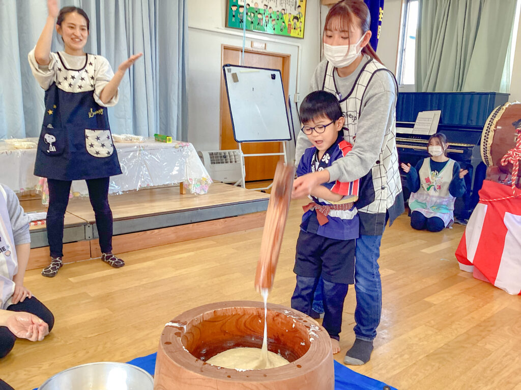 もちつきをする保育士と子ども